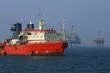 Offshore supply vessel operating near an oil and gas platform to support maintenance, logistics, and energy production activities at sea.